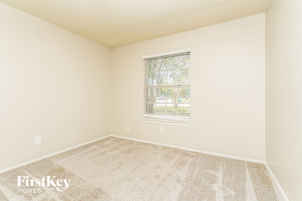 a spacious room with carpet and a window