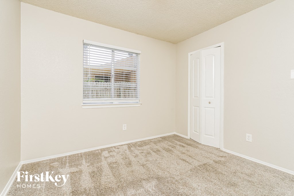 a bedroom with carpet and a window and a door