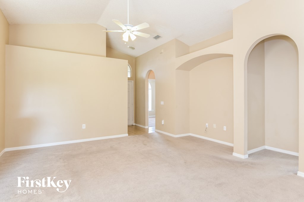 A spacious room with a ceiling fan and beige walls.