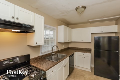 A kitchen with a black stove top oven and a black refrigerator.