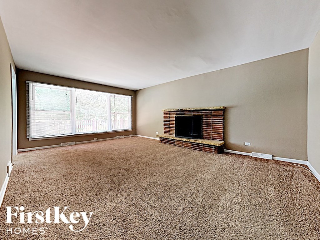an empty living room with a fireplace and a window