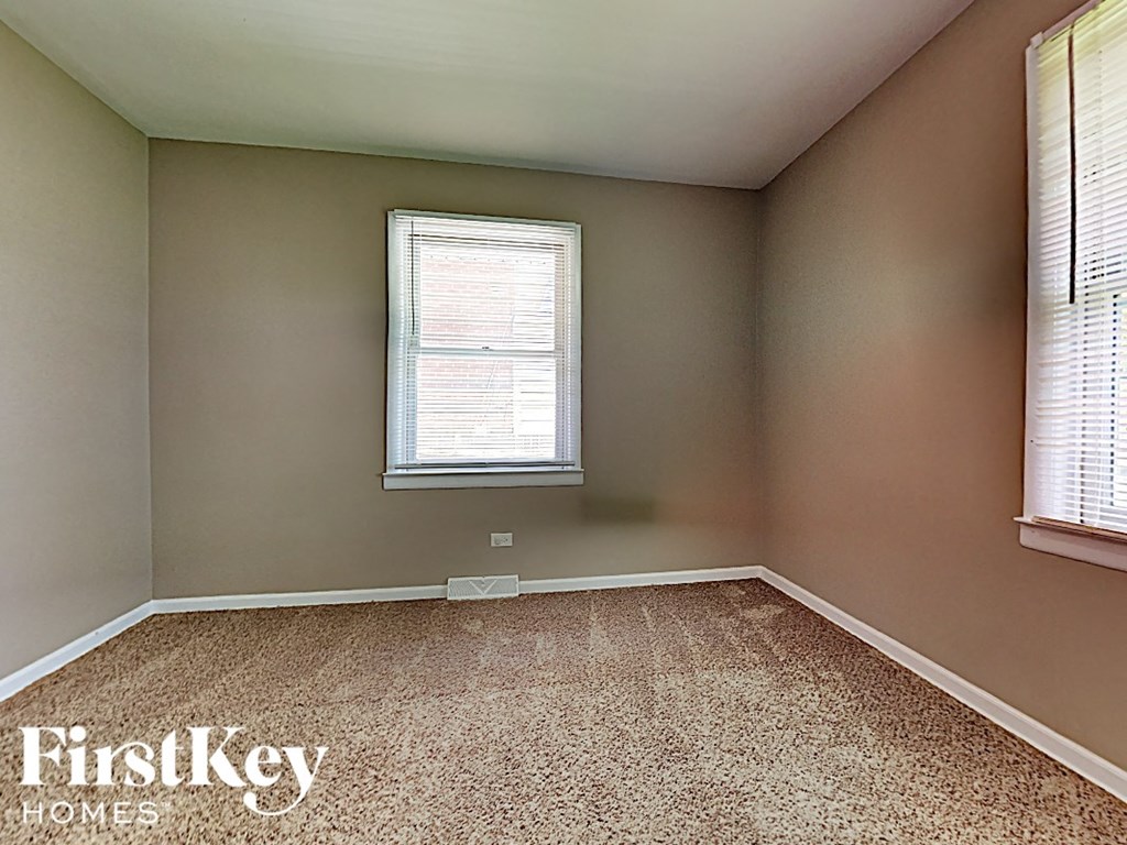 a empty bedroom with two windows and a carpeted floor