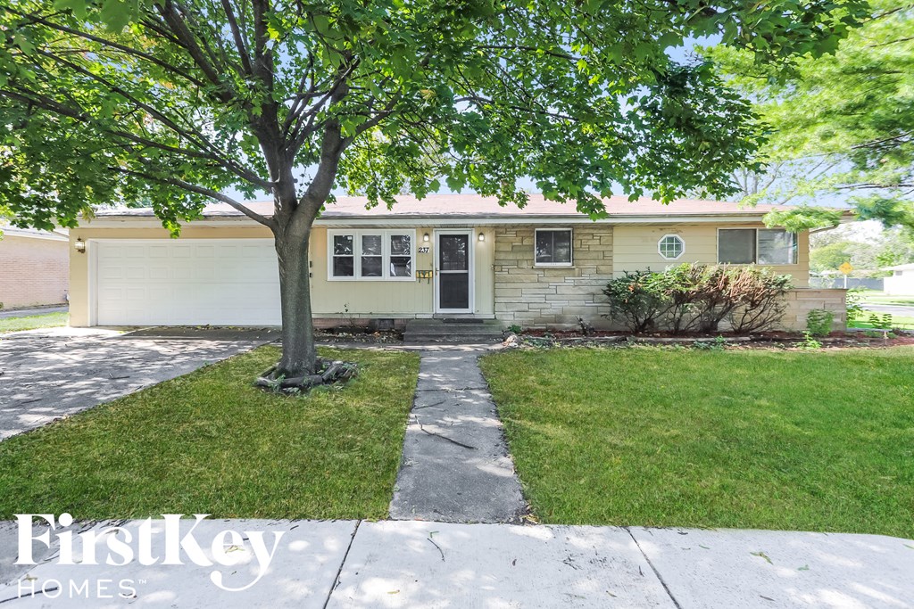 A tree stands in front of a house with a sign that says Firstkey Homes.