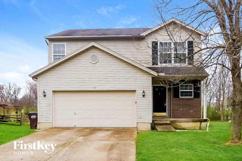 A house with a garage and a tree in front of it.