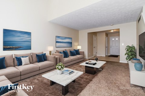 A living room with a large couch, a coffee table, and a painting on the wall.