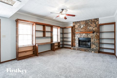 a living room with a stone fireplace and book shelves