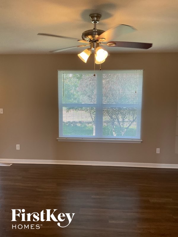 A room with a ceiling fan and a window with blinds.