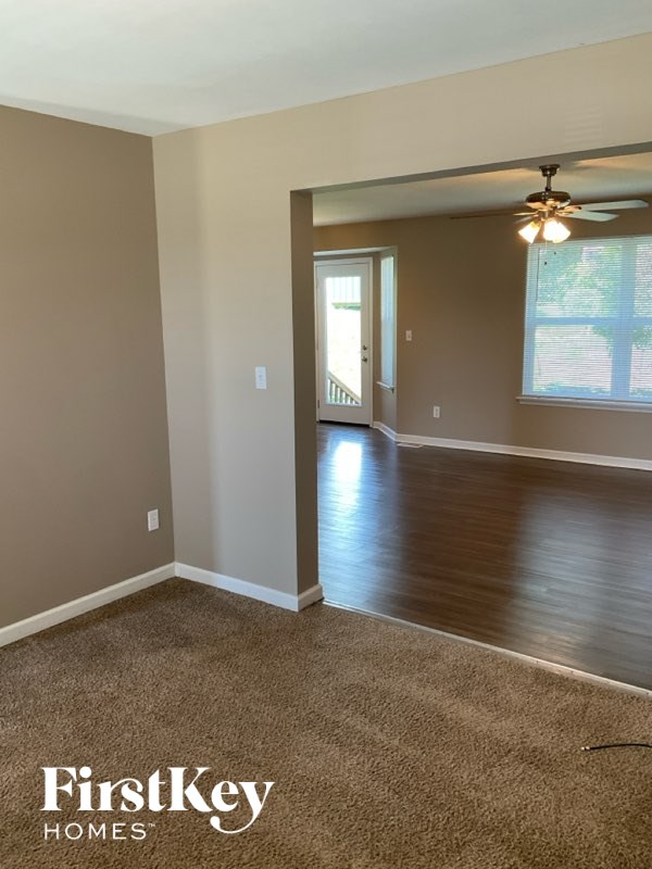A room with a carpeted floor and a ceiling fan.