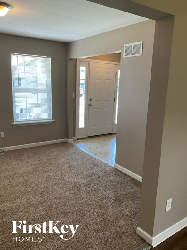 A carpeted room with a doorway leading to another room.