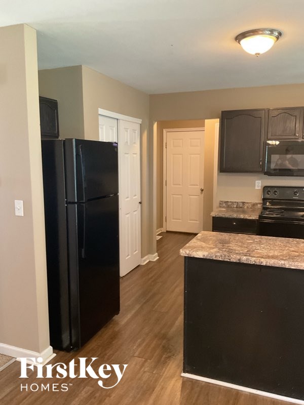 A kitchen with a black fridge and a black counter top.
