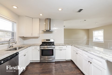 A kitchen with white cabinets and a stainless steel stove top oven.
