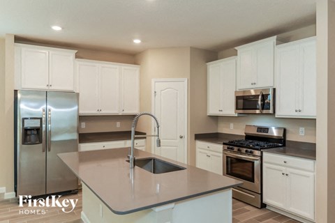 A kitchen with a stainless steel refrigerator, microwave, oven, and sink.