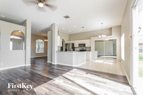 A spacious living room with a kitchen in the background and a FirstKey Homes logo on the floor.