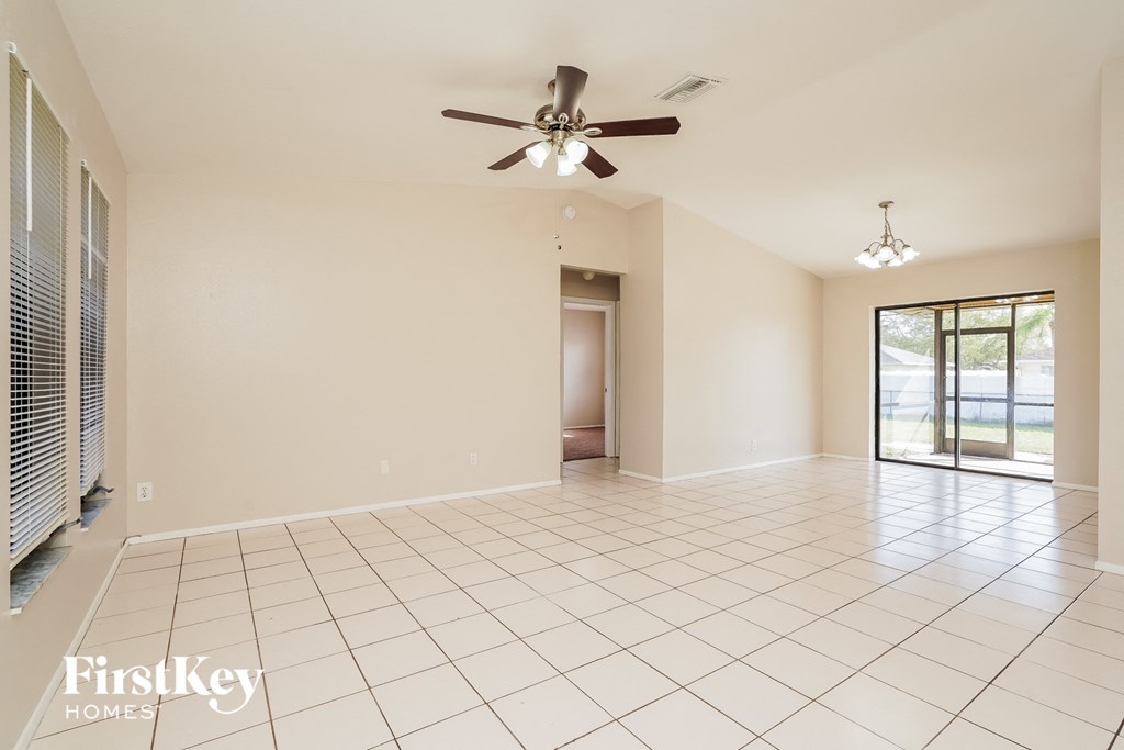an empty living room with a ceiling fan and tiled floor