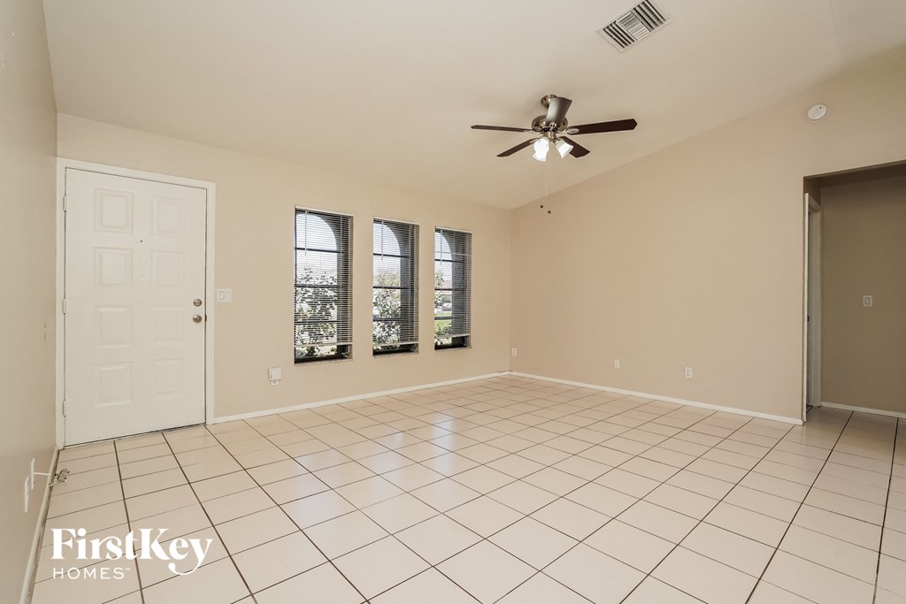 a clean and empty living room with a ceiling fan