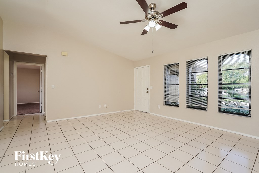 a clean and empty living room with a ceiling fan