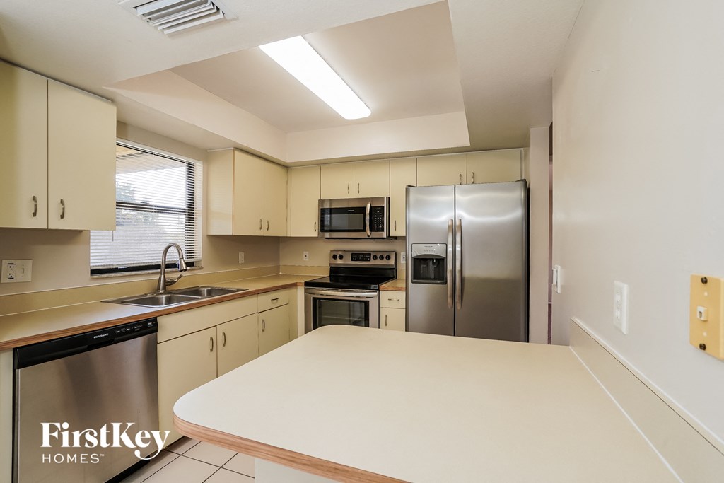 a kitchen with a white counter top and a stainless steel refrigerator