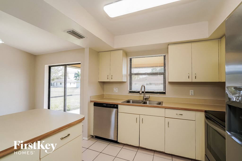 a kitchen with white cabinets and a sink and a window