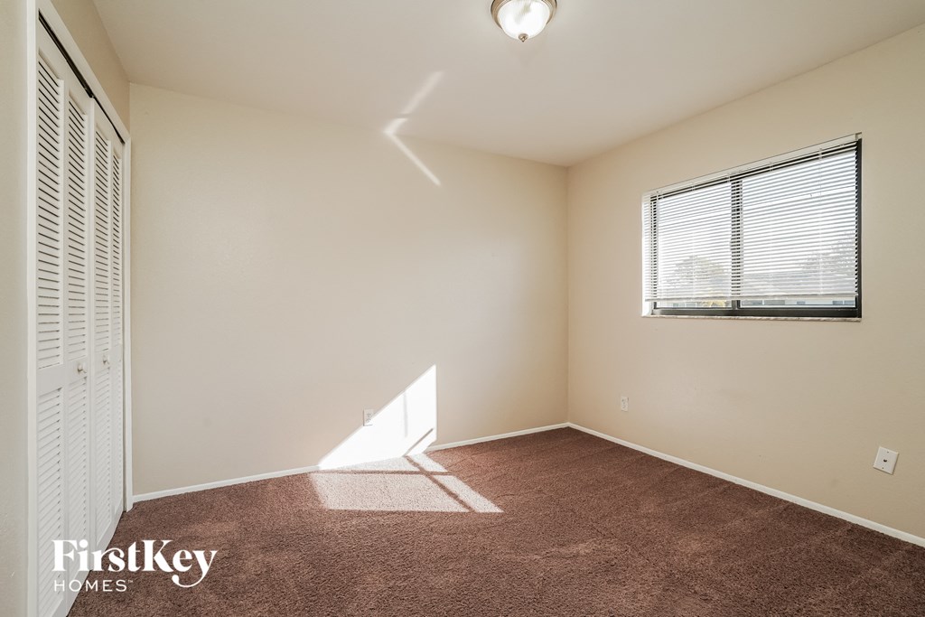 the living room of an empty home with a window and brown carpet