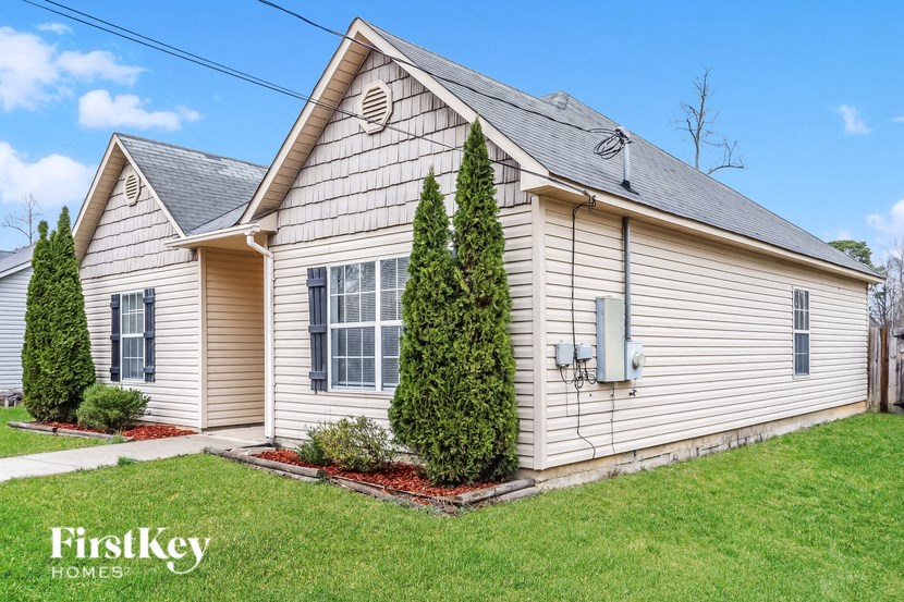 A house with a grey roof and a white siding with a small window and a door.