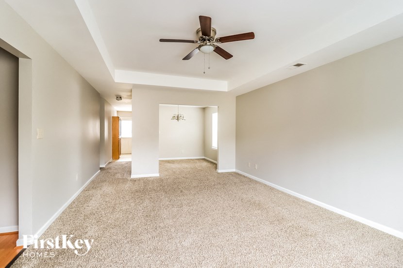 A spacious room with a ceiling fan and carpeted floor.