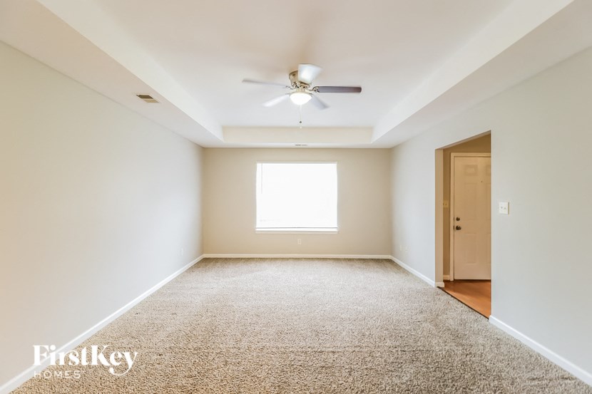 A room with a carpet floor and a ceiling fan.