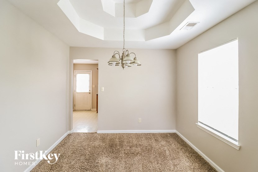A spacious room with a carpeted floor and a chandelier hanging from the ceiling.