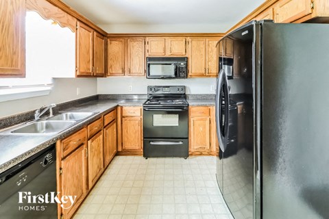 A kitchen with wooden cabinets and a black refrigerator.
