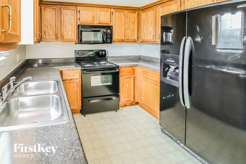 A kitchen with wooden cabinets and a black fridge.