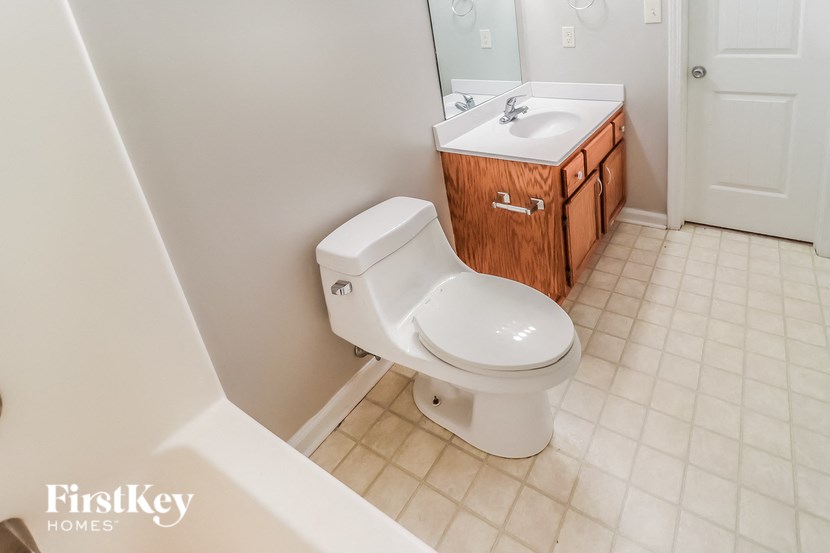 A white toilet in a bathroom with a wooden cabinet above it.