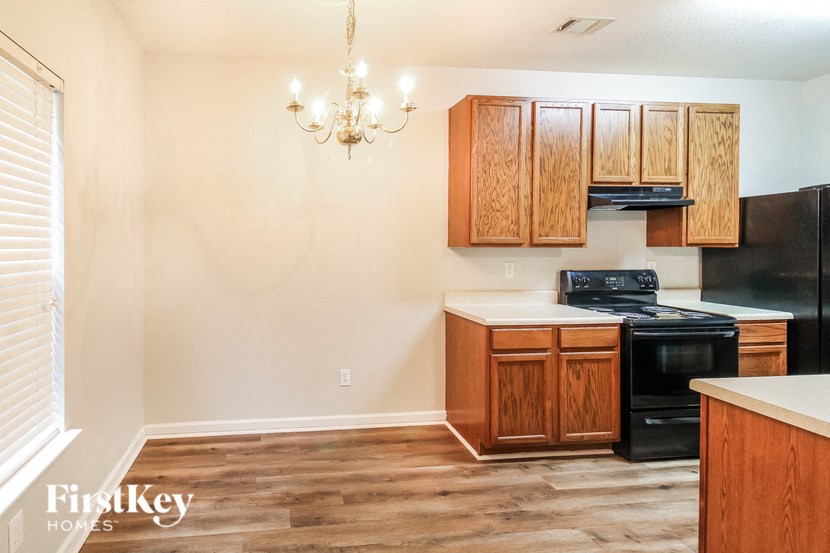 a kitchen with wooden cabinets and black appliances and a chandelier