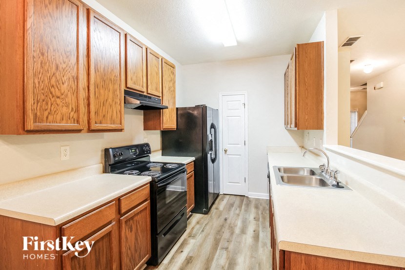 a kitchen with black appliances and wooden cabinets and white counter tops