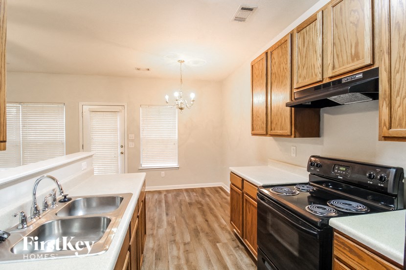 a kitchen with wood cabinets and white counter tops and black appliances