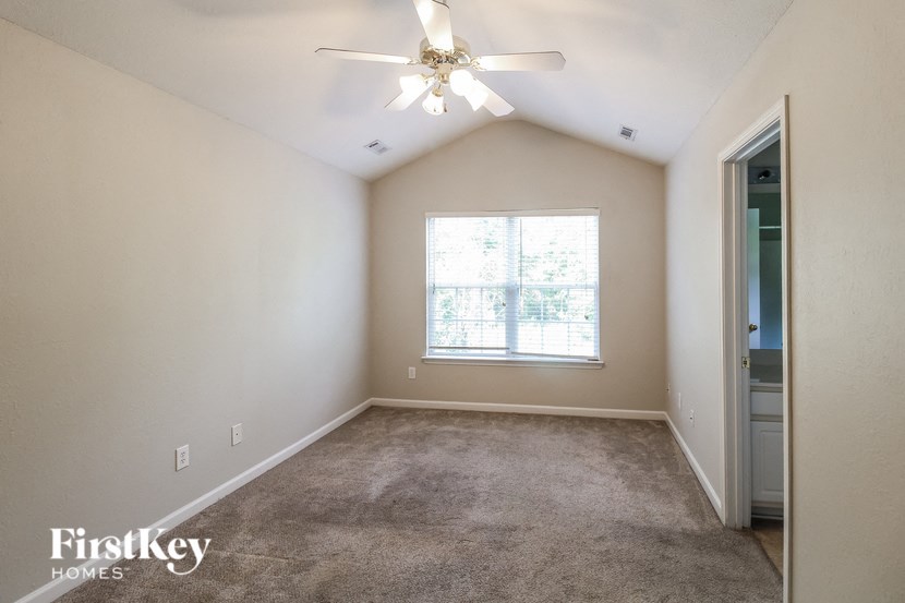 the master bedroom is spacious and has carpeted floors and a ceiling fan