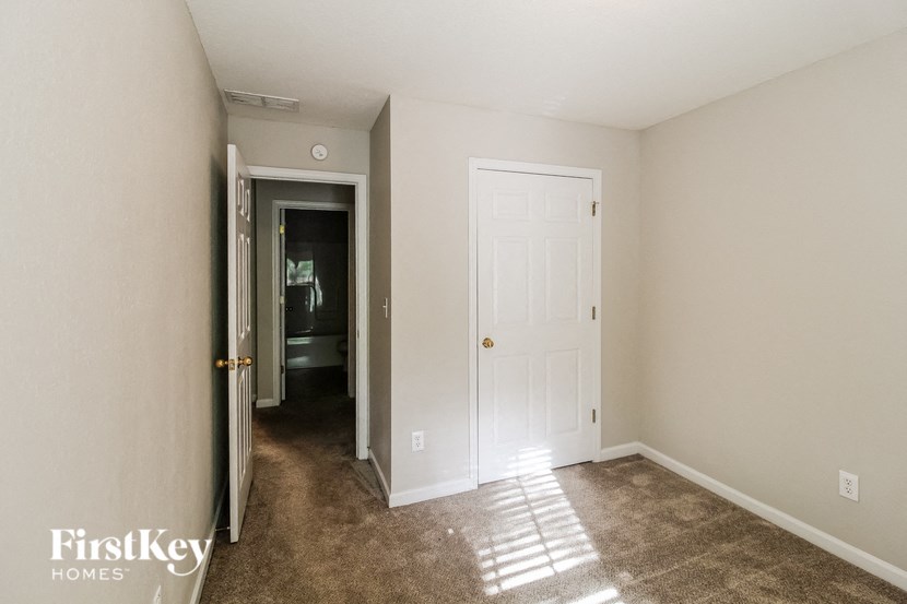 a bedroom with a white door and a carpeted floor