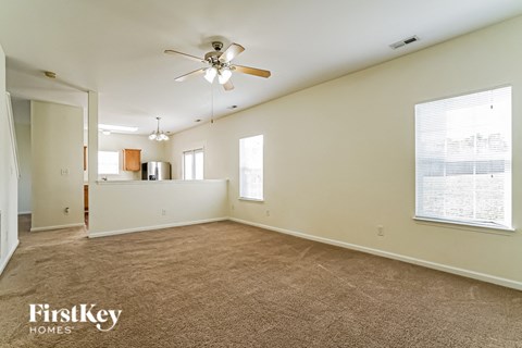 A spacious room with a ceiling fan and carpeted floor.