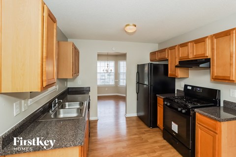 a kitchen with black appliances and wooden cabinets and a wood floor