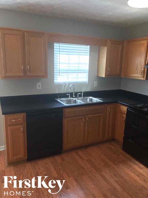 A kitchen with wooden cabinets and black countertops.