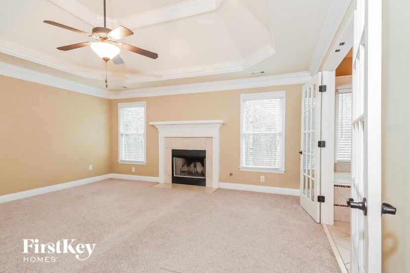 A spacious living room with a fireplace and a ceiling fan.