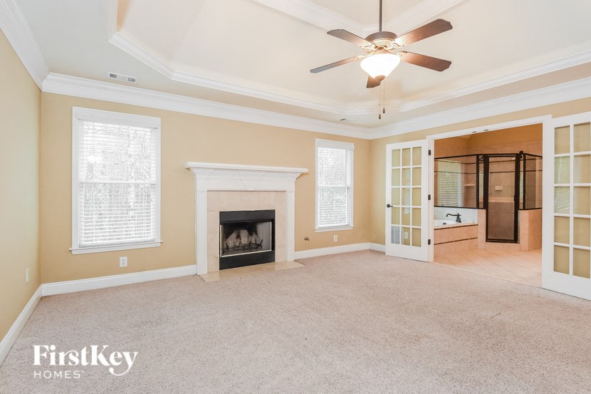 A spacious room with a fireplace and a ceiling fan.