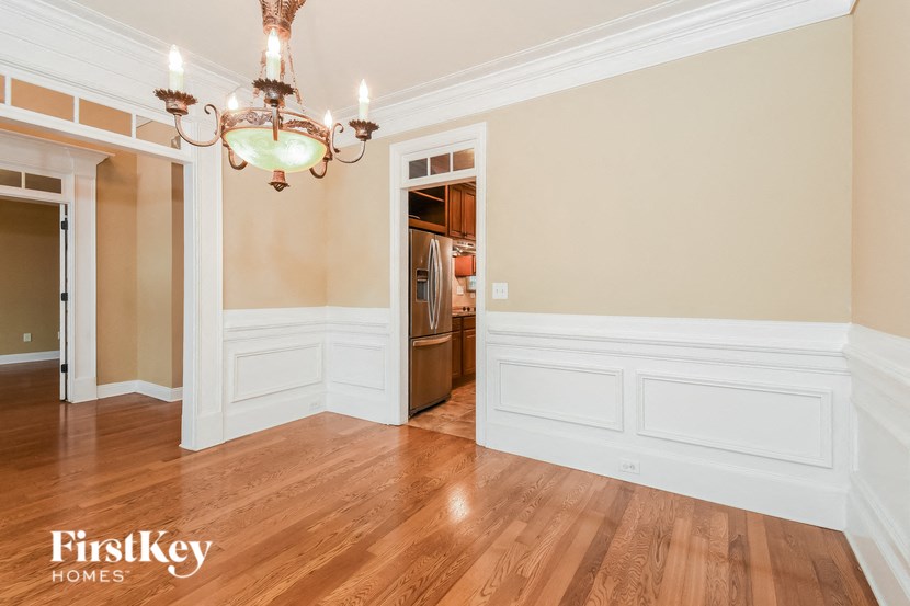 A large, empty room with a chandelier and wood flooring.