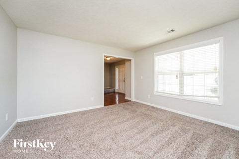A spacious room with a carpeted floor and a doorway leading to another room.