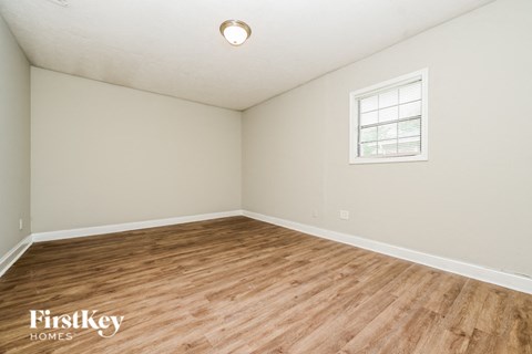 A room with wooden flooring and a window with blinds.