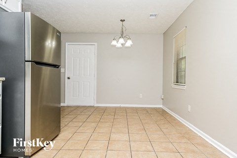 A kitchen with a stainless steel refrigerator and a tile floor.