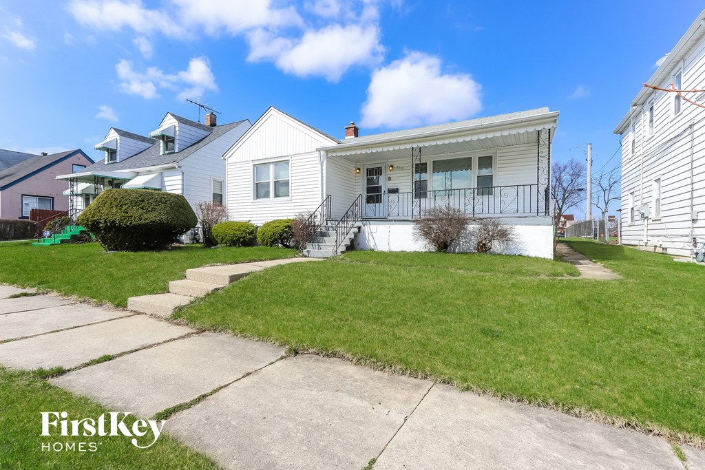 A white house with a green lawn in front of it.