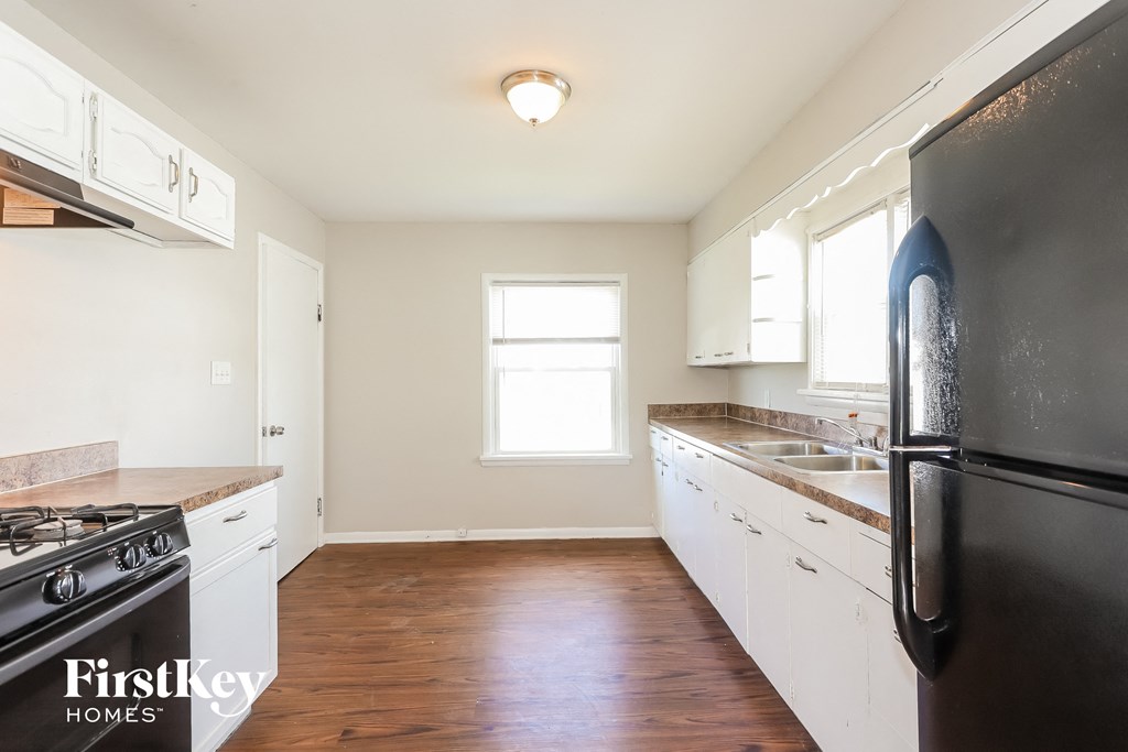 A kitchen with a black fridge and white cabinets.