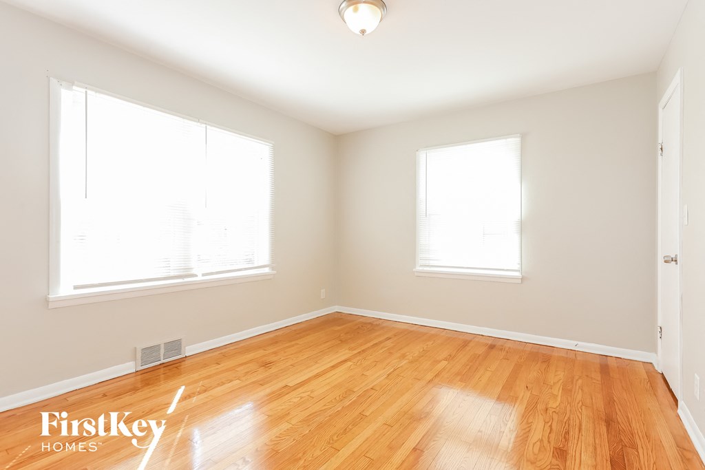 A room with wooden floors and two windows.