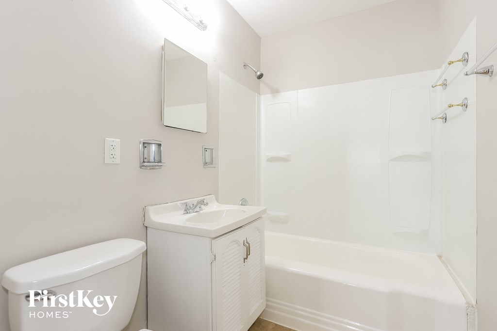 A white bathroom with a tub, toilet, and sink.