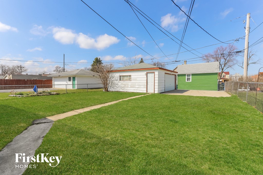 A grassy yard with a house and a tree in the background.