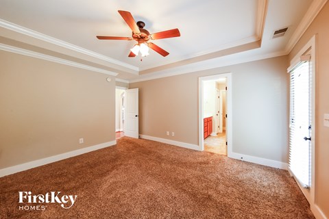 a master bedroom with carpet and a ceiling fan